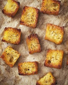 Croûtons sucrés au Air Fryer, cubes dorés croustillants, légèrement caramélisés, saupoudrés d'épices et d'herbes sucrées.