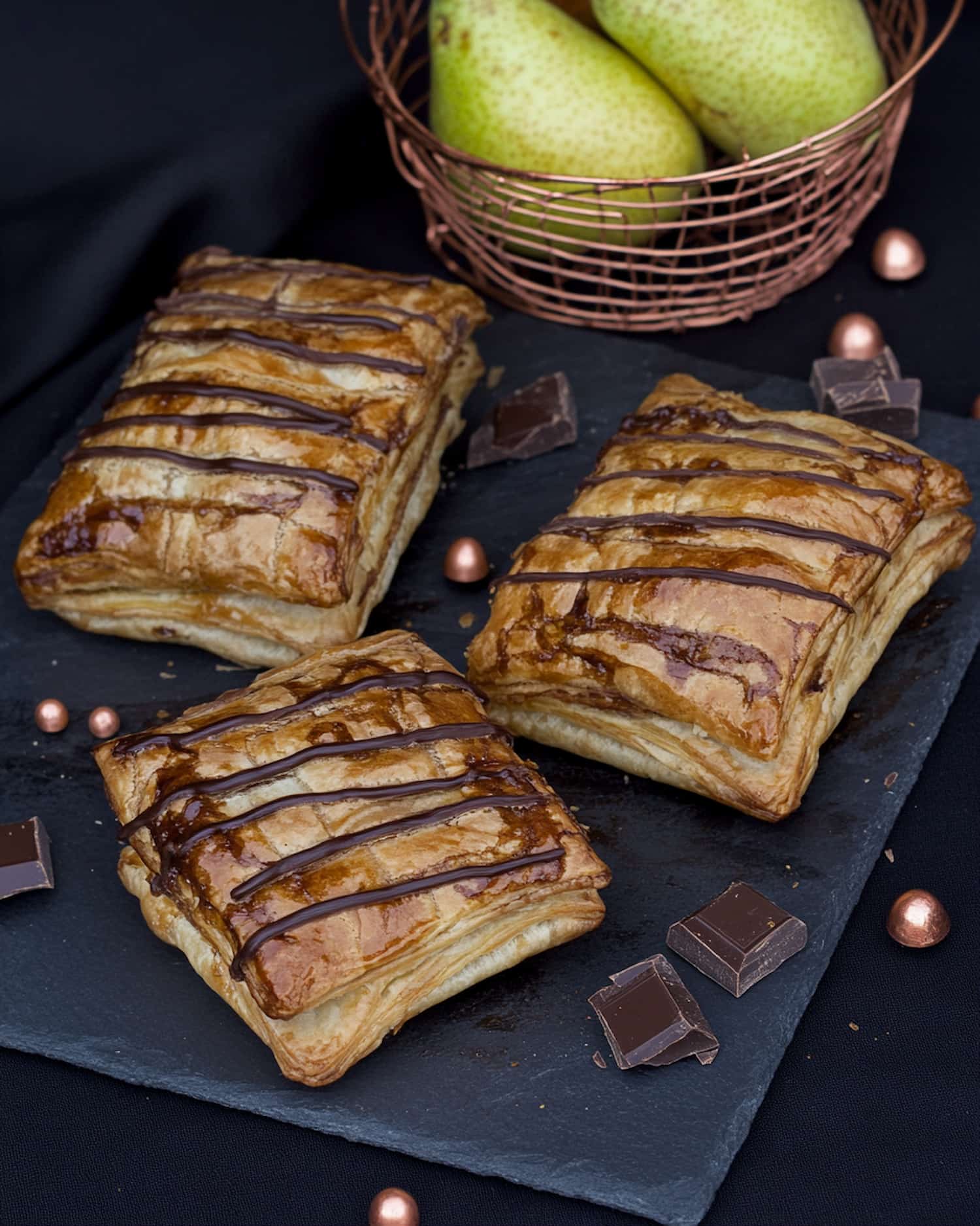 Chaussons poire chocolat au Air Fryer, dorés et nappés de chocolat fondu. Carrés de chocolat et poires fraîches en décor.