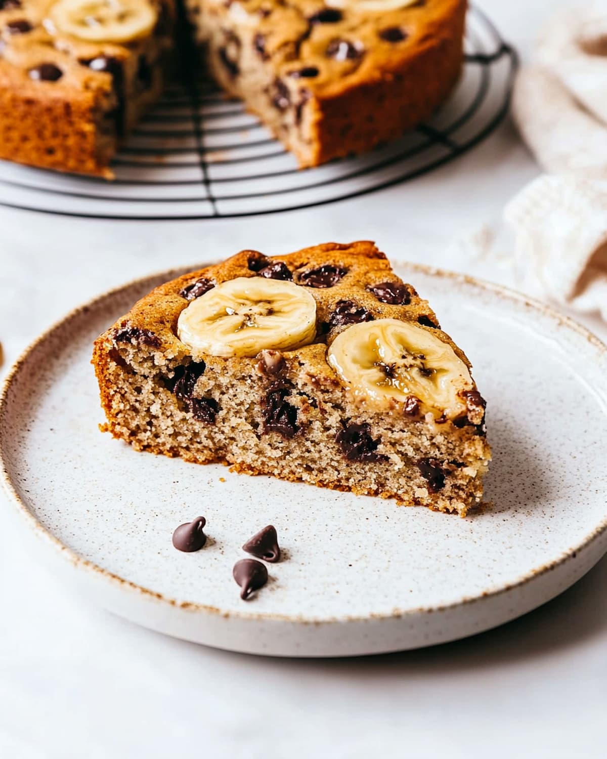 Part de gâteau banane chocolat au Air Fryer, décorée de rondelles de banane et pépites.