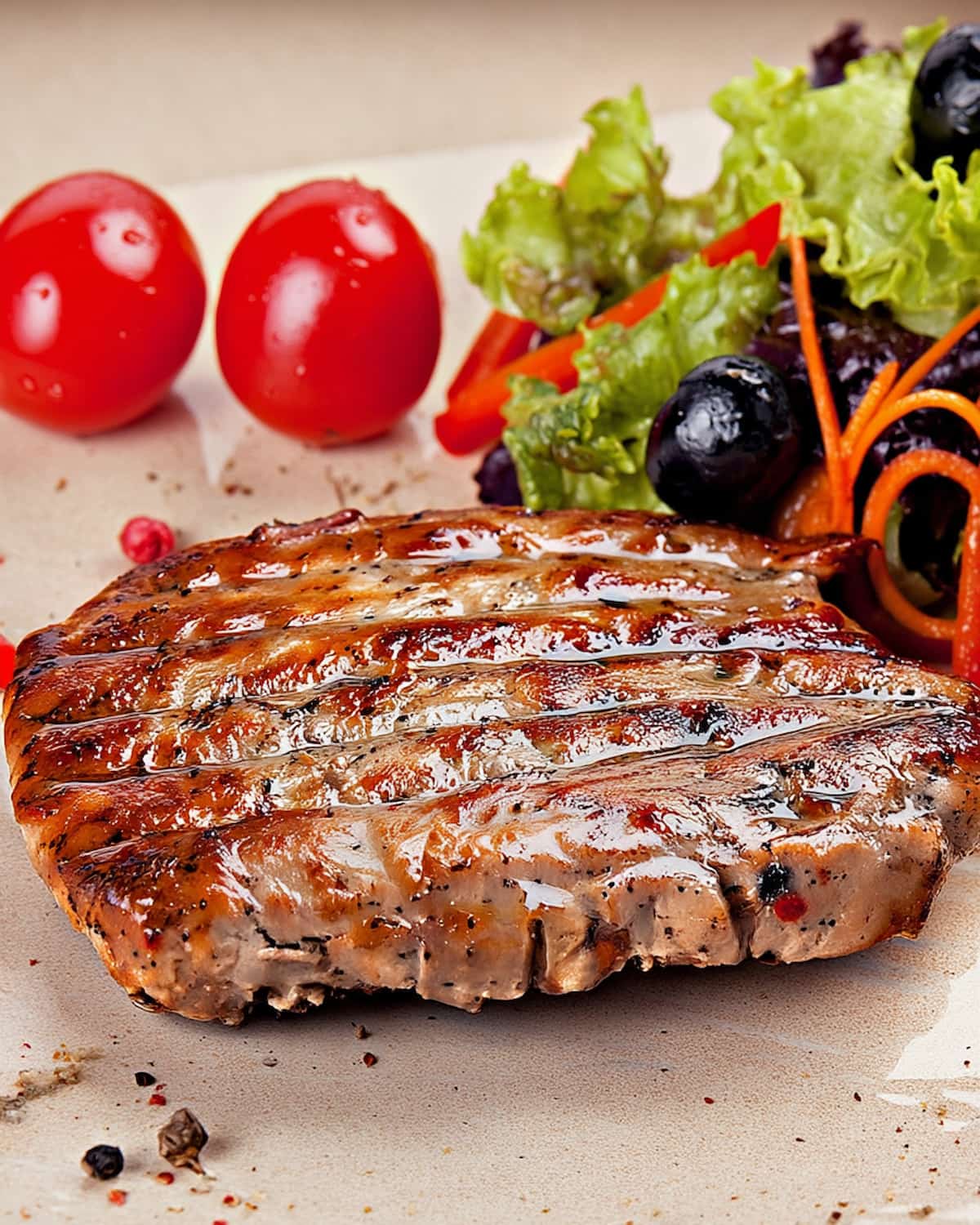 Assiette avec un steak haché surgelé au Air Fryer bien grillé, accompagné de salade fraîche, tomates cerises et olives noires.