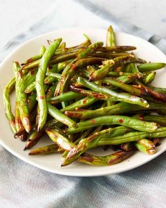 Assiette de haricots verts au Air Fryer, légèrement grillés et assaisonnés.