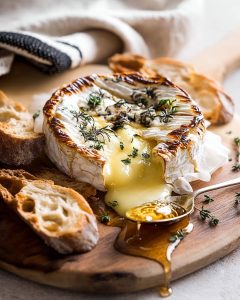 Camembert au Air Fryer fondu, garni de thym, servi sur planche avec miel coulant et tranches de pain croustillant.