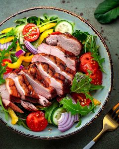 Assiette de magret de canard au Air Fryer, tranché et servi sur un lit de salade.