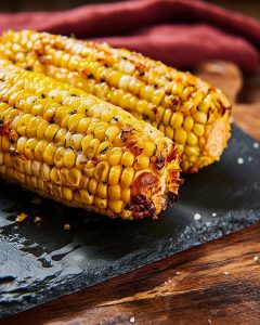 Épi de maïs sucré au beurre au Air Fryer, bien doré, nappé de beurre fondu et d’herbes.