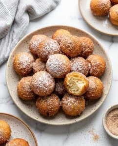Beignets à l’air fryer moelleux, dorés et roulés au sucre-cannelle, servis en bouchées sur une assiette