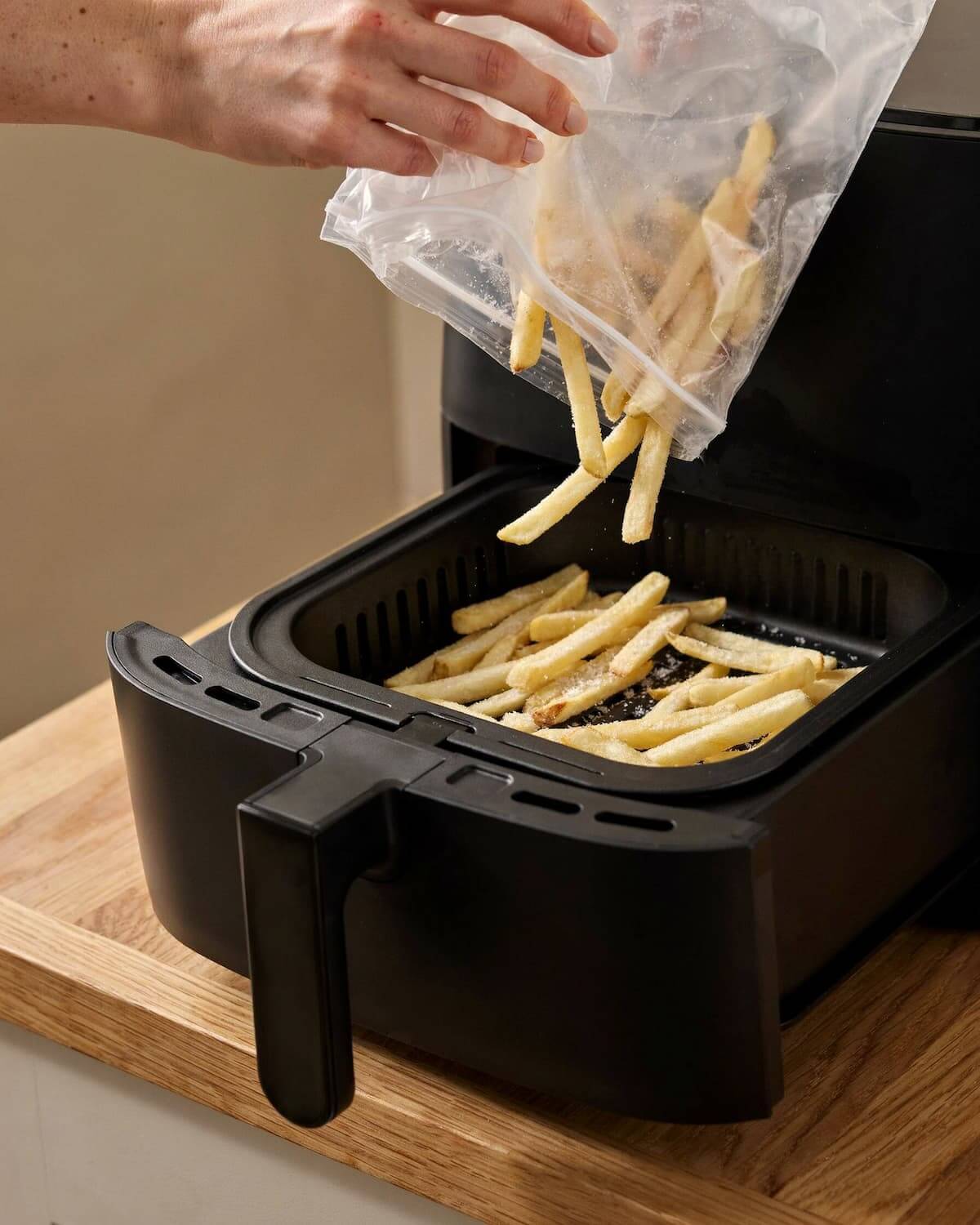 Frites surgelées givrées versées d’un sachet dans le panier d’un air fryer